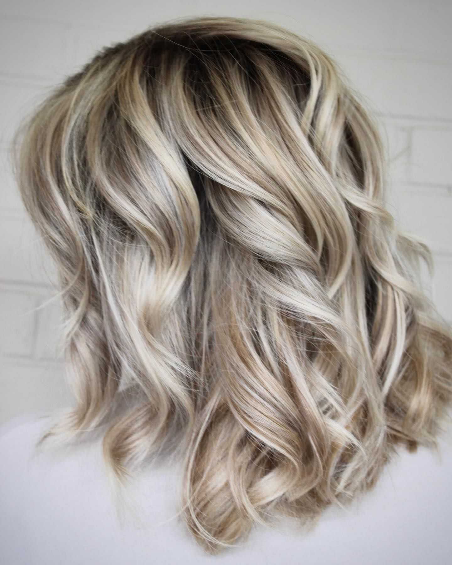 Wavy balayage hairstyle with blond highlights.