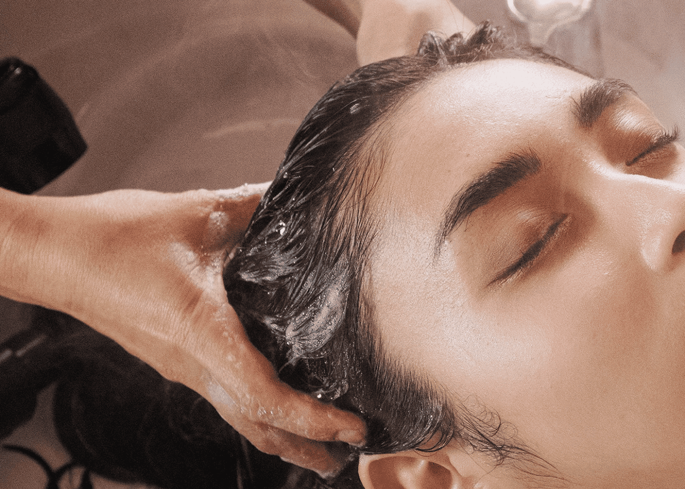 Person receiving a relaxing hair wash with closed eyes in a salon.